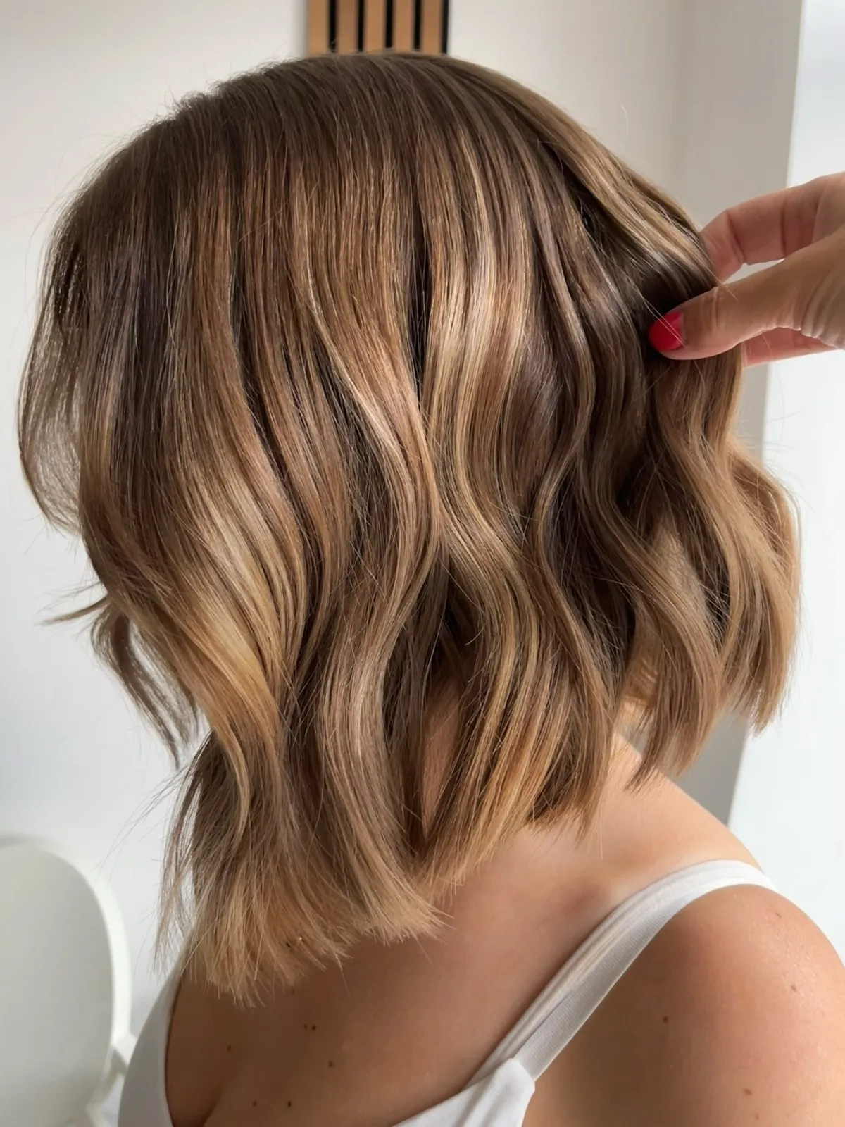 Side view of a warm dimensional bronde lob with caramel and glossy waves.
